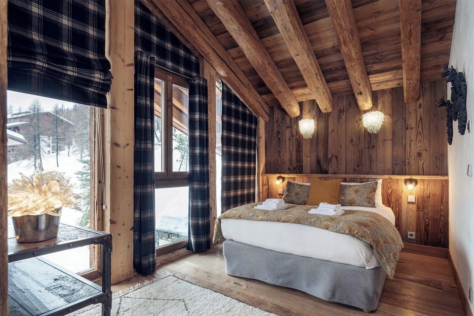 Retreat to a beautifully appointed bedroom where bespoke décor, cozy textiles, and stunning views create a serene alpine sanctuary at Chalet Genepy.