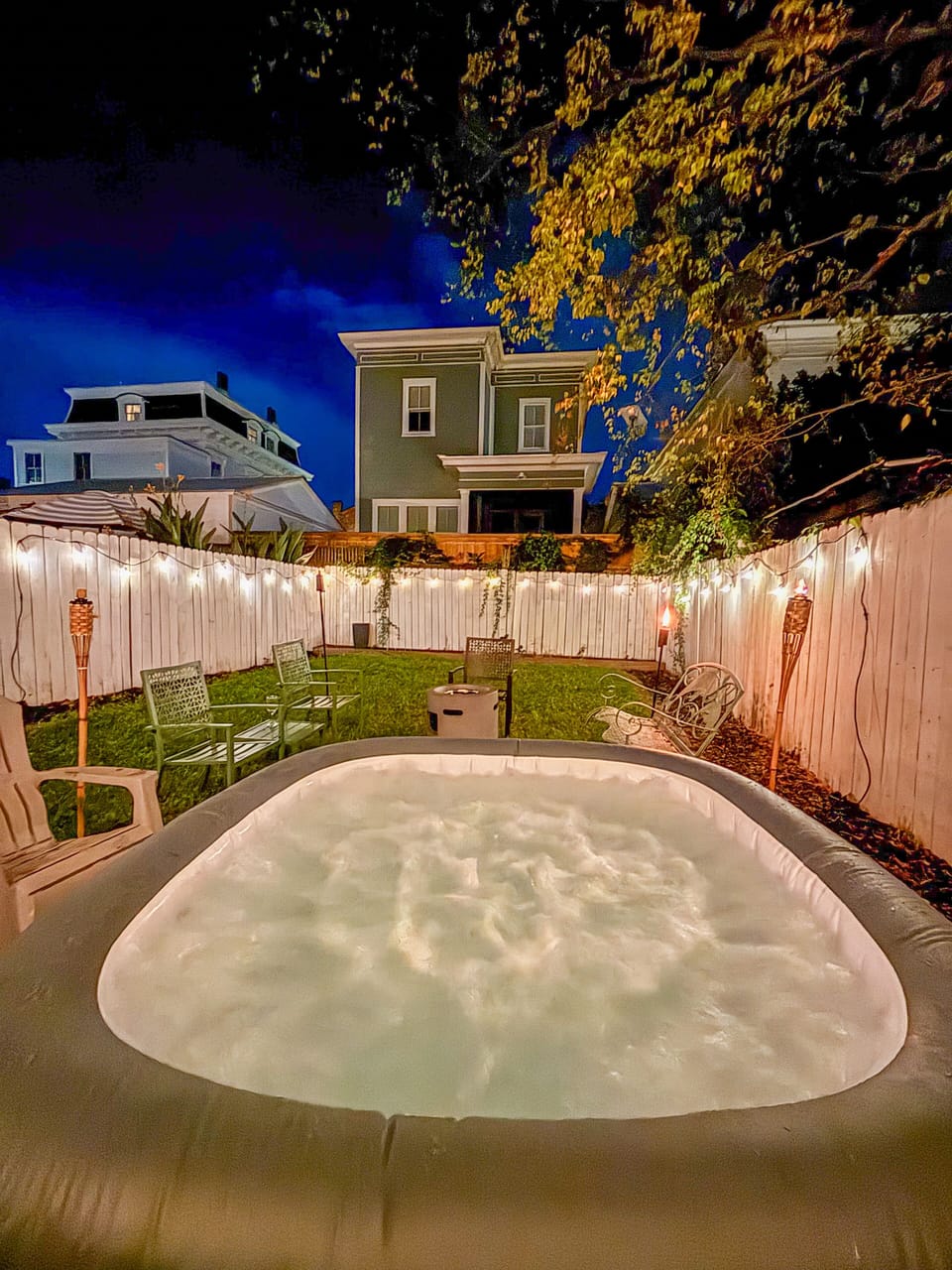 Private fenced-in backyard featuring a relaxing hot tub and cozy firepit.