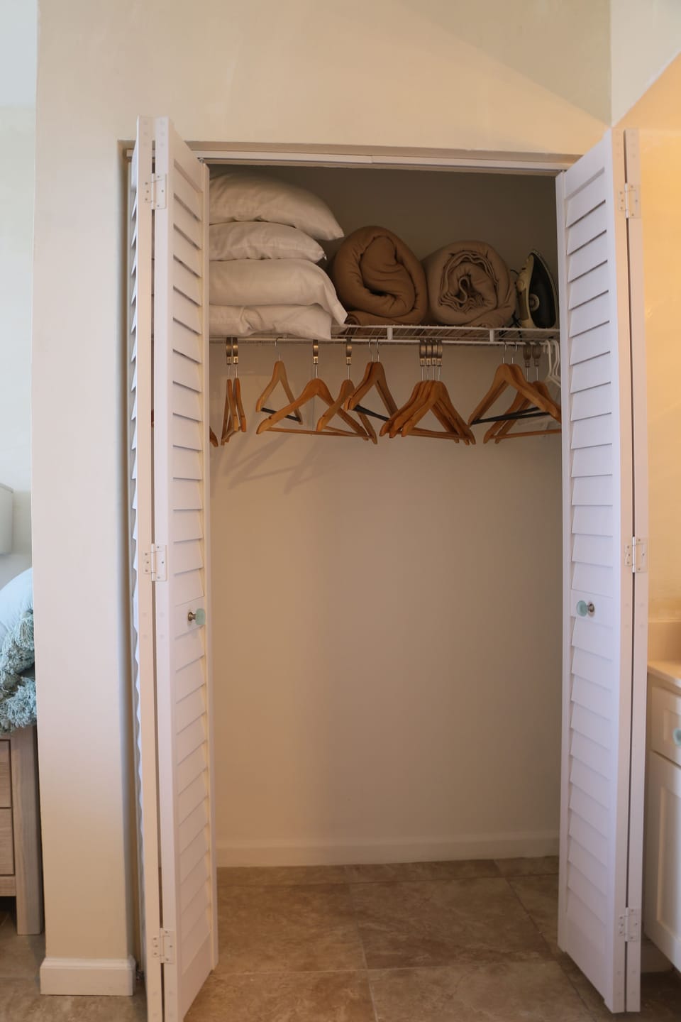 master closet with extra blankets, pillows, hangers, iron and board