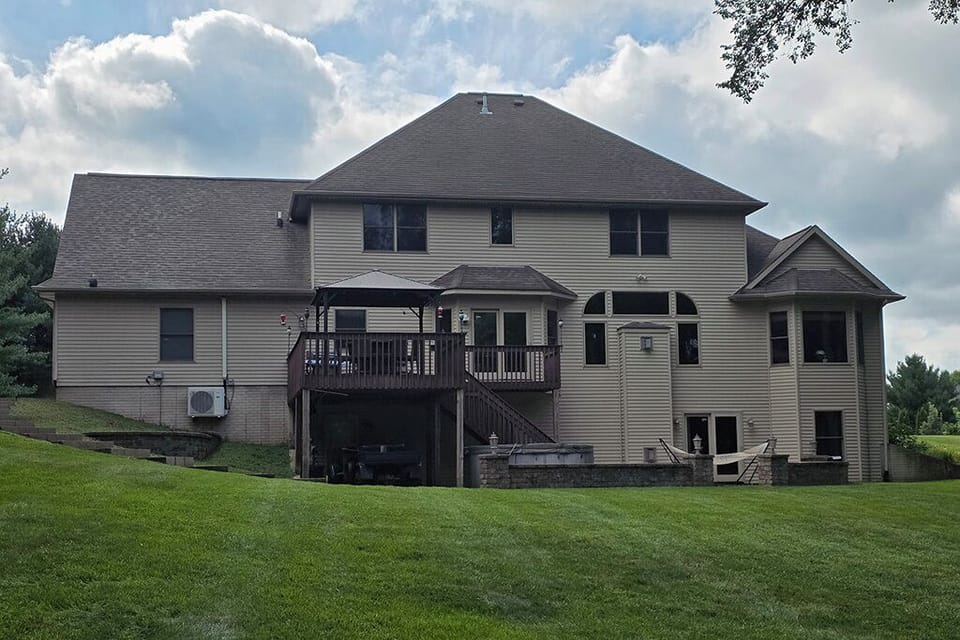 Rear view of house with deck, patio, hot tub and hammock.