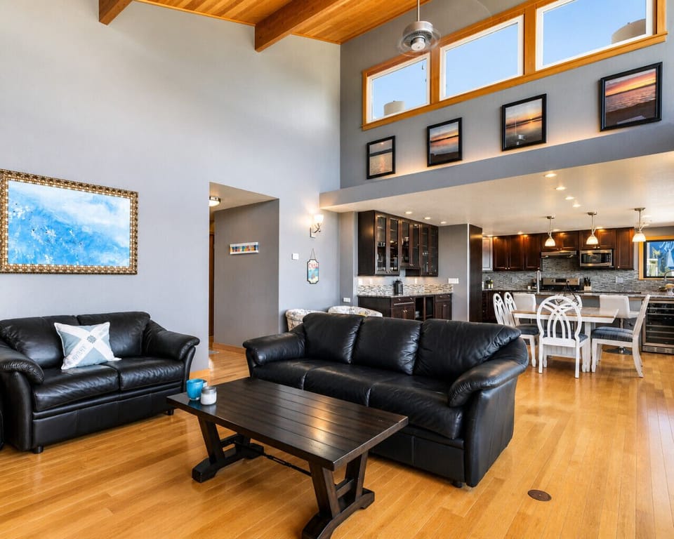 Expansive Living Room with High Ceilings, Warm Wood Floors, & Seamless Flow into Kitchen