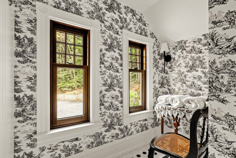 Bunk room bathroom with beautiful wallpaper and small getting ready area by large windows with natural light 