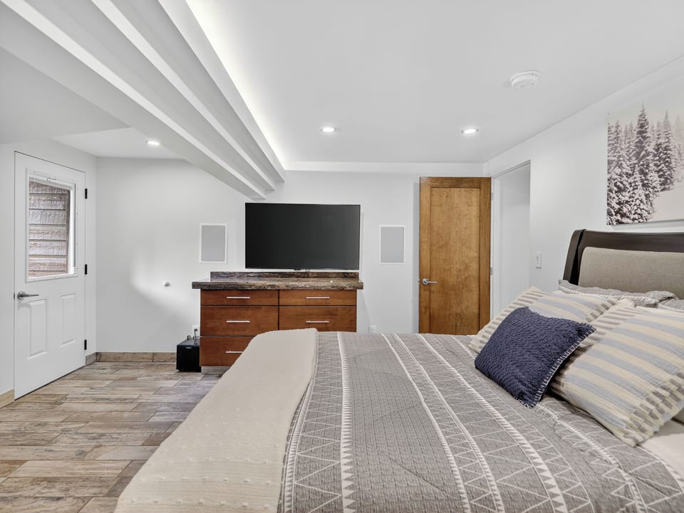 Third bedroom featuring a queen-size bed, smart TV, seating area, and a private en suite bathroom