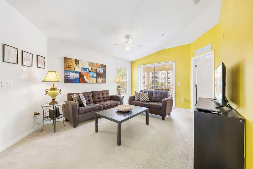 Spacious living area with comfortable sofas, a flat-screen TV, and plenty of natural light—perfect for relaxing after a day at the parks.