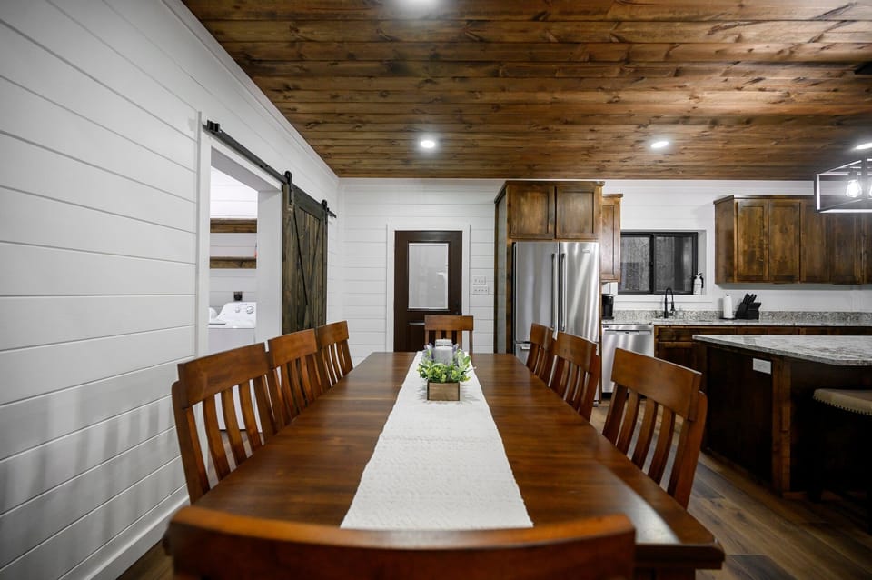 Wood beams, granite island, barn door—warm dining space with cozy charm.