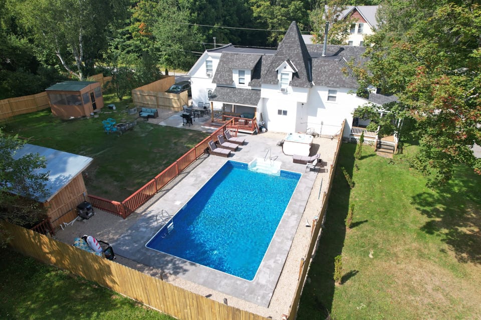 View of the back yard with pool, hot tub, enclosed patio, fire pit and even hammocks.