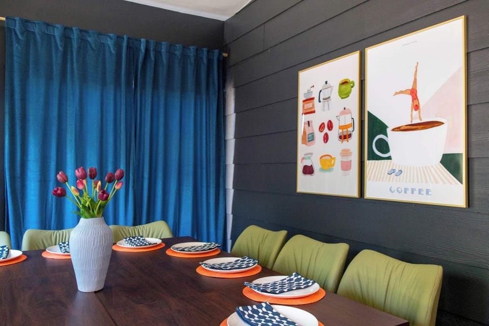 Spacious dining room with large table, blue curtains, and colorful seating for group gatherings.