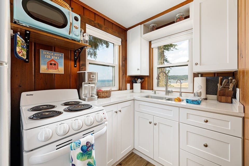 Charming kitchen w/ white cabinets, gas stove & lake views to enjoy while you cook.