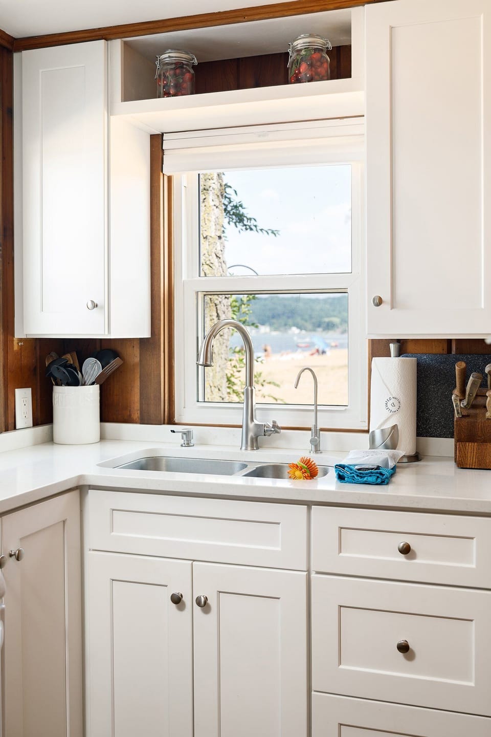 Bright kitchen sink w/ wide window views of the beach & lake beyond.