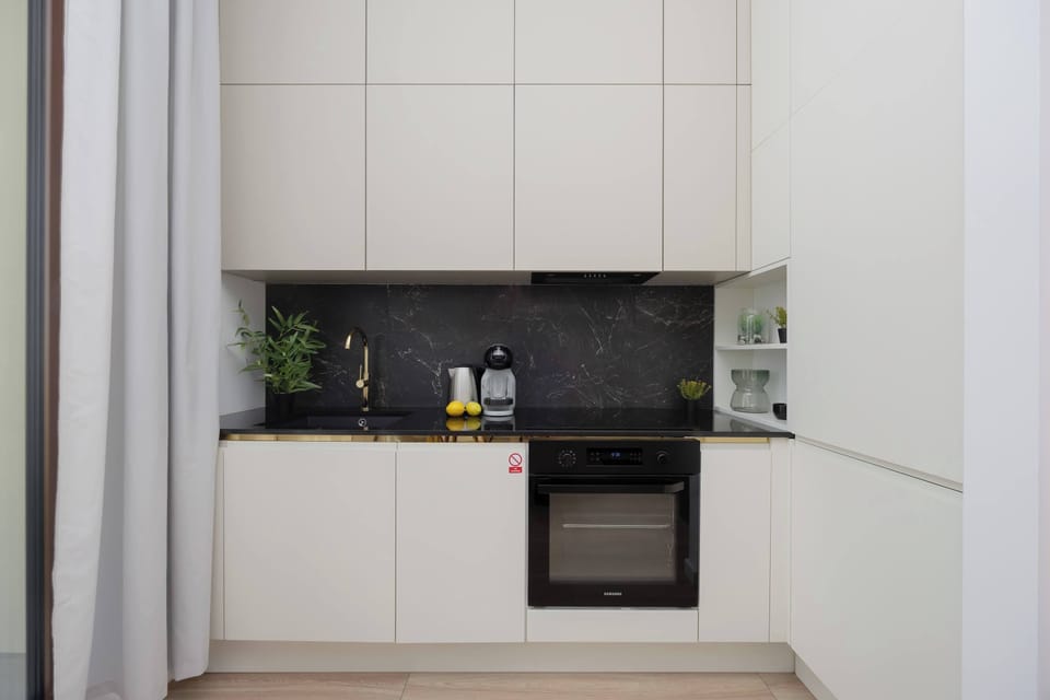 Modern kitchen with white cabinetry, black backsplash, and a built-in oven.