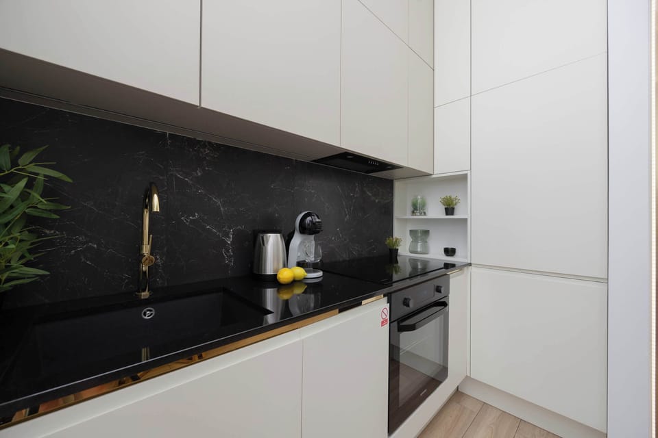 Sleek kitchen with built-in appliances, white cabinets, and black backsplash.