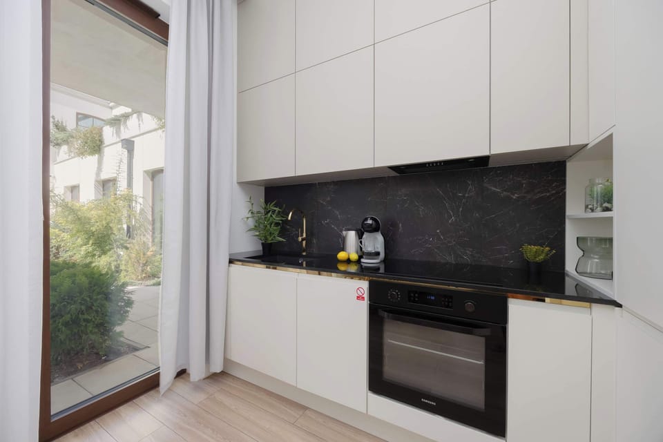 Modern kitchen with white cabinetry, black backsplash, and a built-in oven.