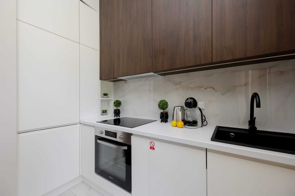 Bright and compact kitchenette equipped with essential appliances, black sink fittings, and a sleek, minimalistic design.