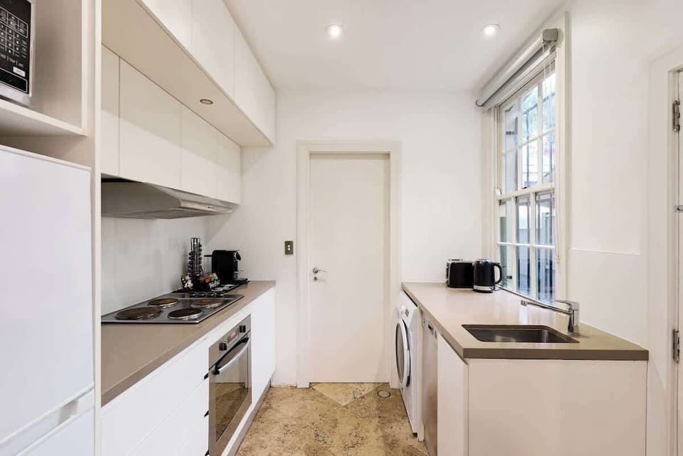 Bright galley kitchen with full cooking facilities, microwave, dishwasher, and washing machine. Everything needed for convenient self-catering during your Woolloomooloo stay.