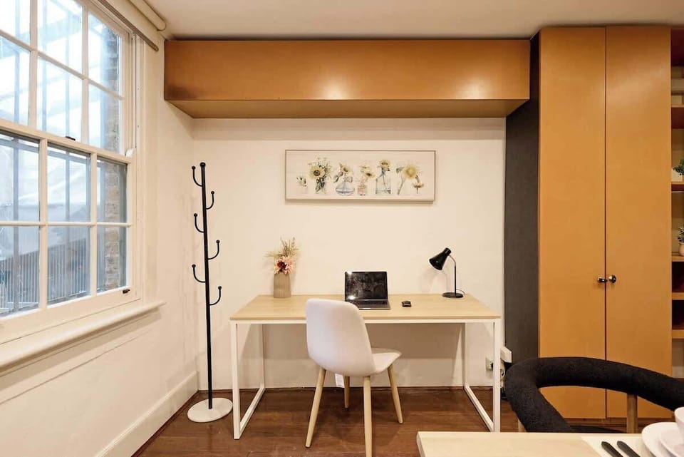 Modern workspace with large heritage windows overlooking Cathedral Street. Clean desk setup with task lighting and coat rack, perfect for business travelers or planning Sydney adventures.