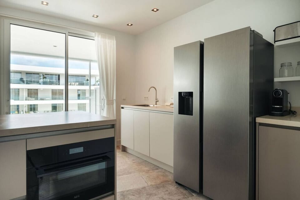 Prepare your favorite meals in this sleek, modern kitchen, featuring high-end stainless steel appliances and a view of the terrace through the glass doors.