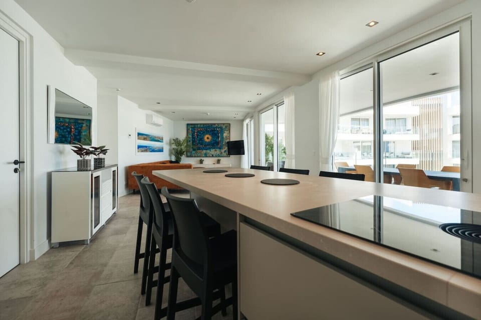 Pull up a stool at this spacious kitchen island, perfect for a quick breakfast or casual conversation while overlooking the open-concept living area and the sunny terrace beyond.