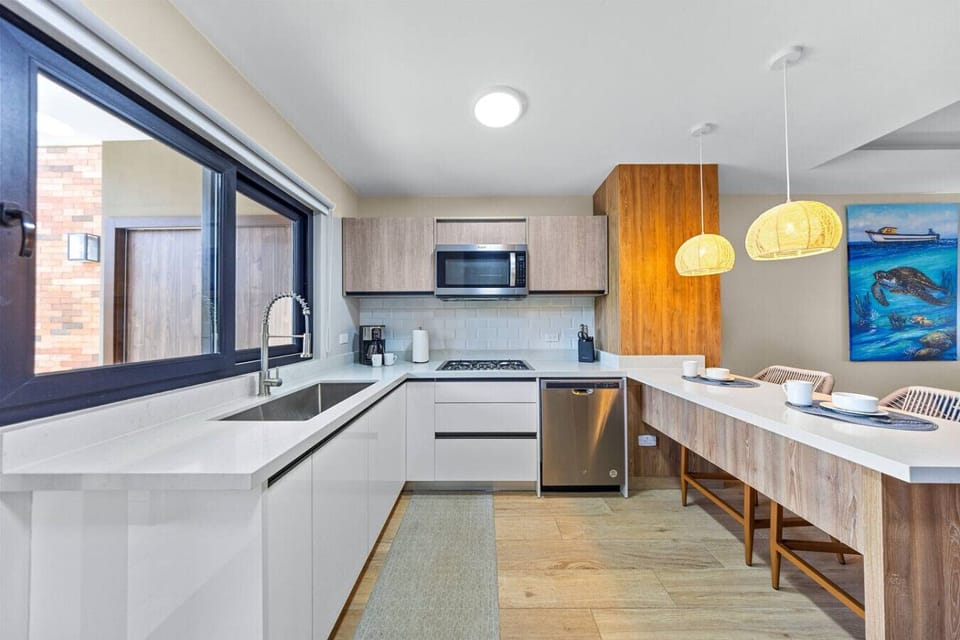 kitchen with white cabinets, stainless steel appliances, a sleek sink, and a window that opens to a bright outdoor space, with two woven placemats.