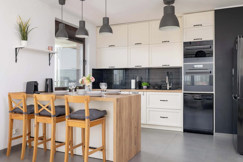 A bright kitchen corner with wooden countertops, open shelves, and stylish black lamps.