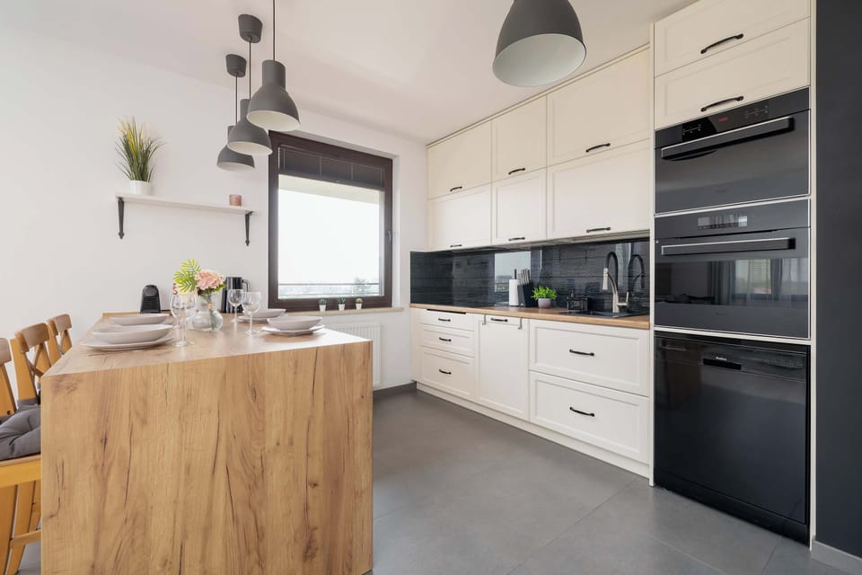 A sleek kitchen with cream cabinets, black countertops, and built-in appliances.