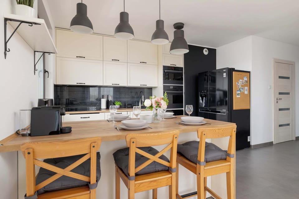 A bright kitchen corner with wooden countertops, open shelves, and stylish black lamps.