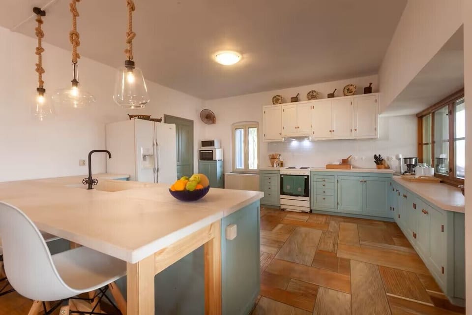 Kitchen view from dining area; oversized counters with four bar stools.