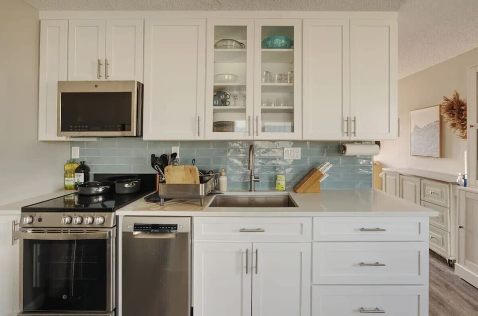 Bright modern kitchen with stainless appliances and stylish blue backsplash