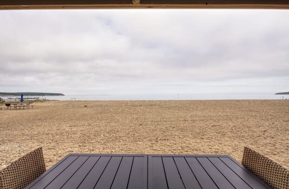 Beachfront patio dining with sweeping sandy shore and water views