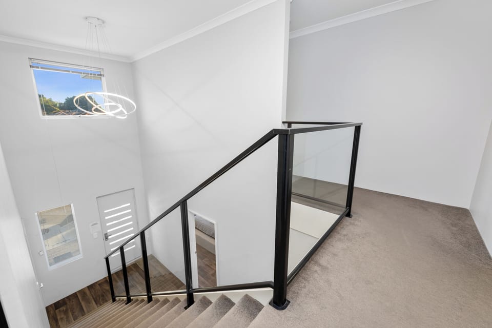Our modern staircase, illuminated by a contemporary light fixture, invites you to explore all the comforts this home has to offer. 