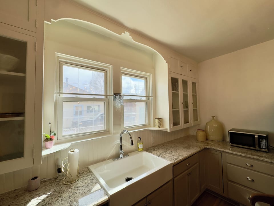 Warm sunlit farmhouse sink, in fully equipped kitchen
