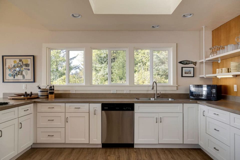Bright and airy, this kitchen offers plenty of counter space and natural light from the large windows. It’s well-stocked and designed to make cooking and gathering together simple and enjoyable.