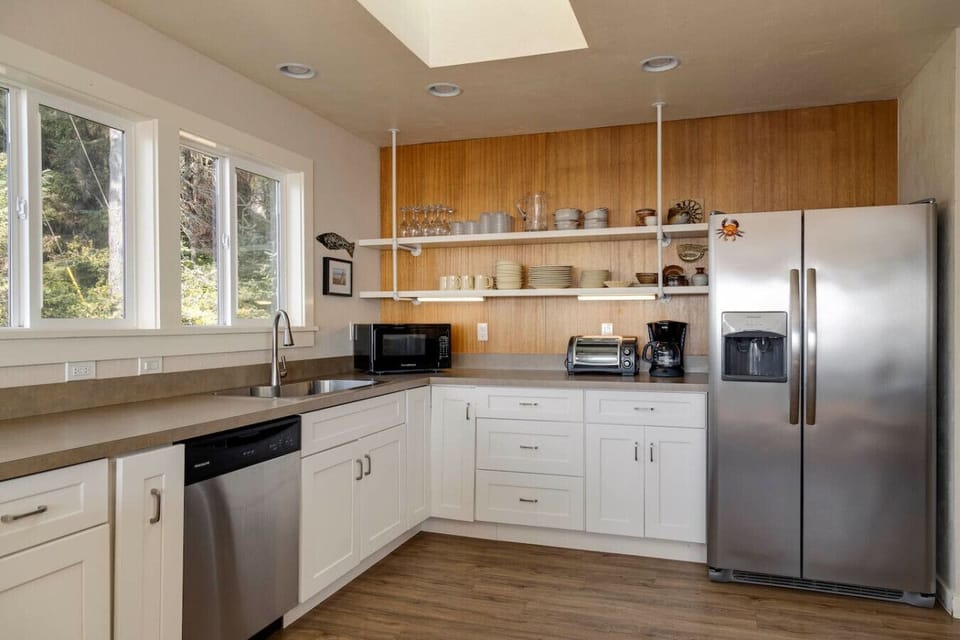 Enjoy the ease of a fully equipped kitchen with modern stainless steel appliances and open shelving stocked with essentials. Whether brewing morning coffee or preparing dinner, this space makes every meal feel effortless.