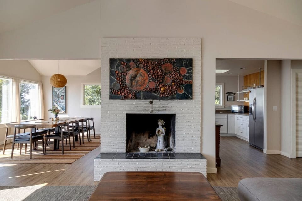 This decorative fireplace adds character and charm to the heart of the home. Its central placement creates a warm, inviting atmosphere that ties the living, dining, and kitchen spaces together.
