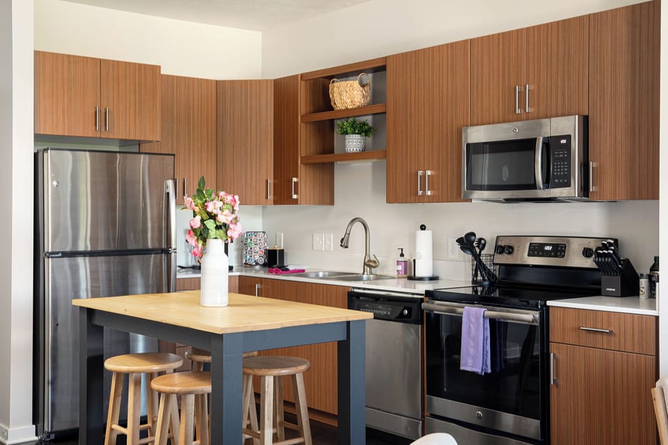 Stylish kitchen w/ wood cabinets, stainless steel appliances & island seating for easy meals