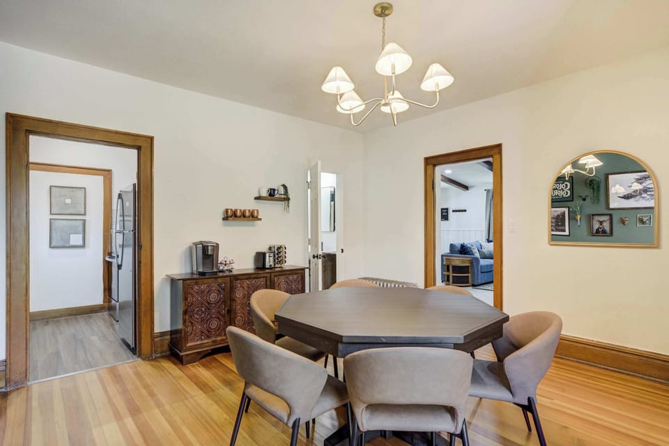 The dining area combines style and function with a modern chandelier, bold accent wall, and a versatile table that transforms into a poker table for game nights.