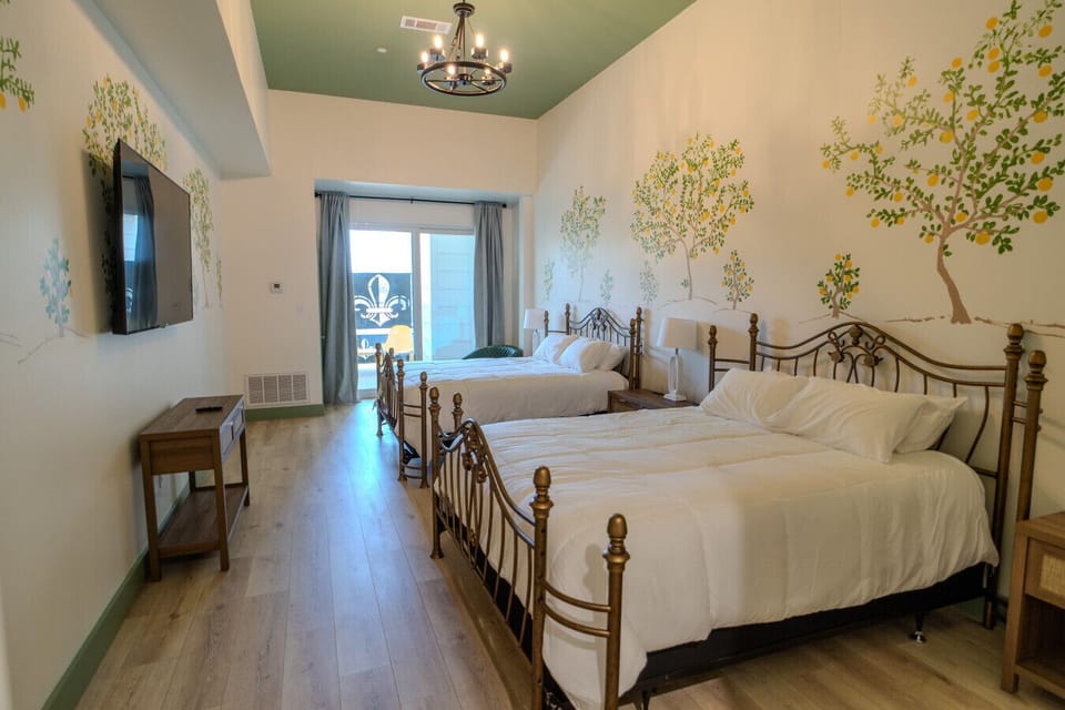 This spacious guest room features two full beds, cheerful wall art, and a private balcony — perfect for families or small groups