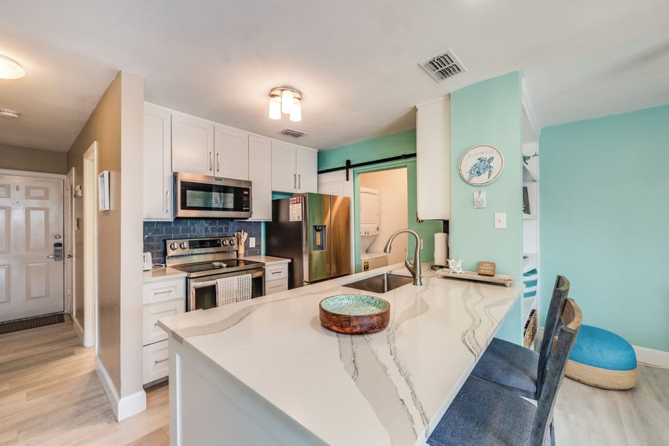 Your modern kitchen awaits with sleek marble counters, stainless appliances, and cheerful mint walls that make cooking feel like a coastal escape.