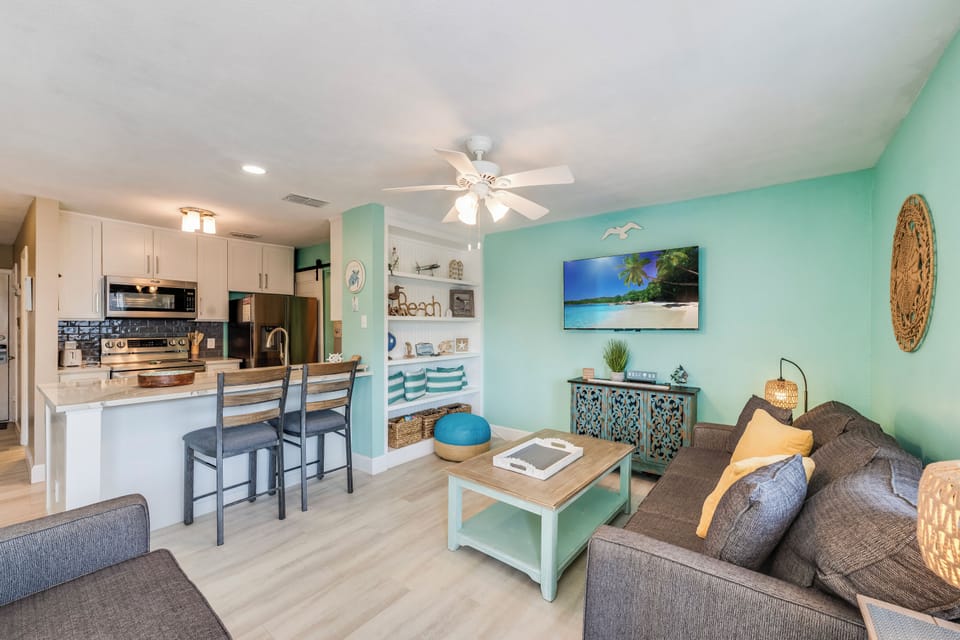 Relax in your bright, coastal-themed living space where soft mint walls and beach decor create a serene atmosphere for your getaway.