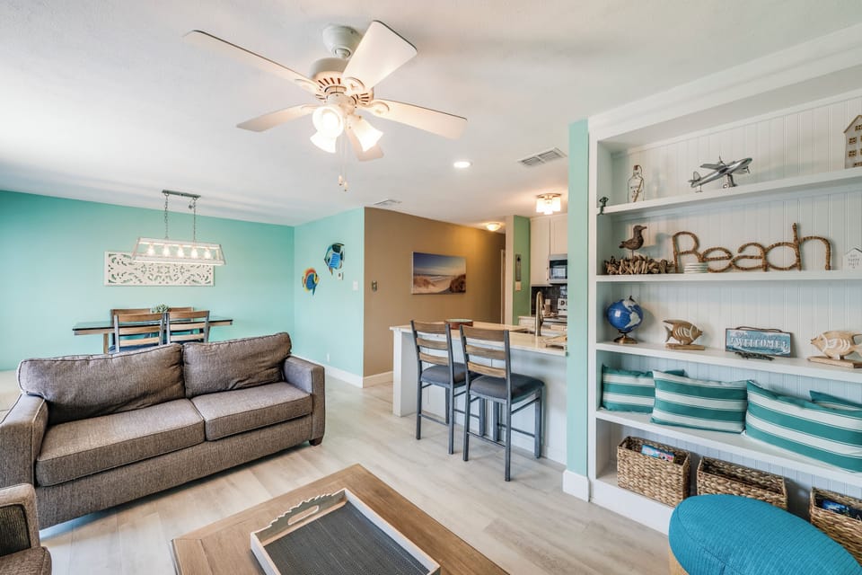 Relax in your bright beach-themed living space with cozy seating, ocean-inspired decor, and an open layout connecting to your dining area.