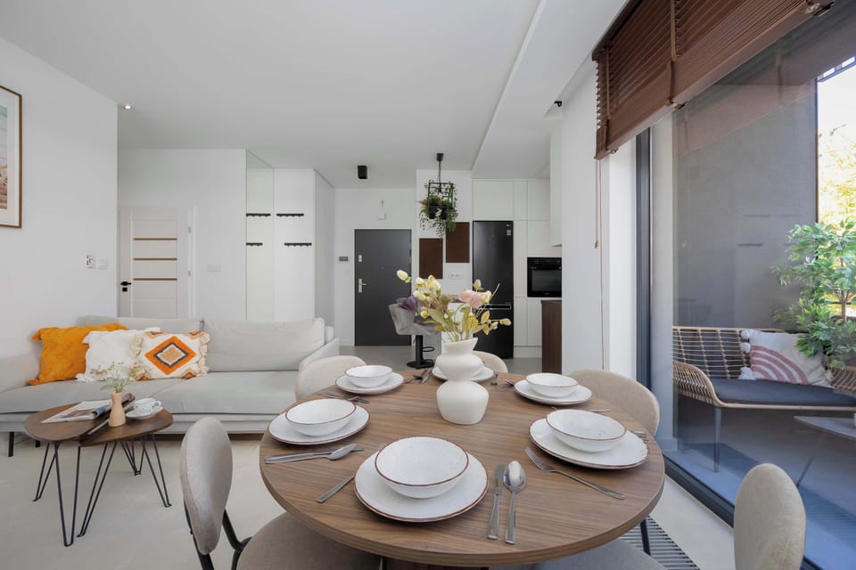 The round dining table set for a meal by the window offers the perfect spot for shared breakfasts with a view of greenery.