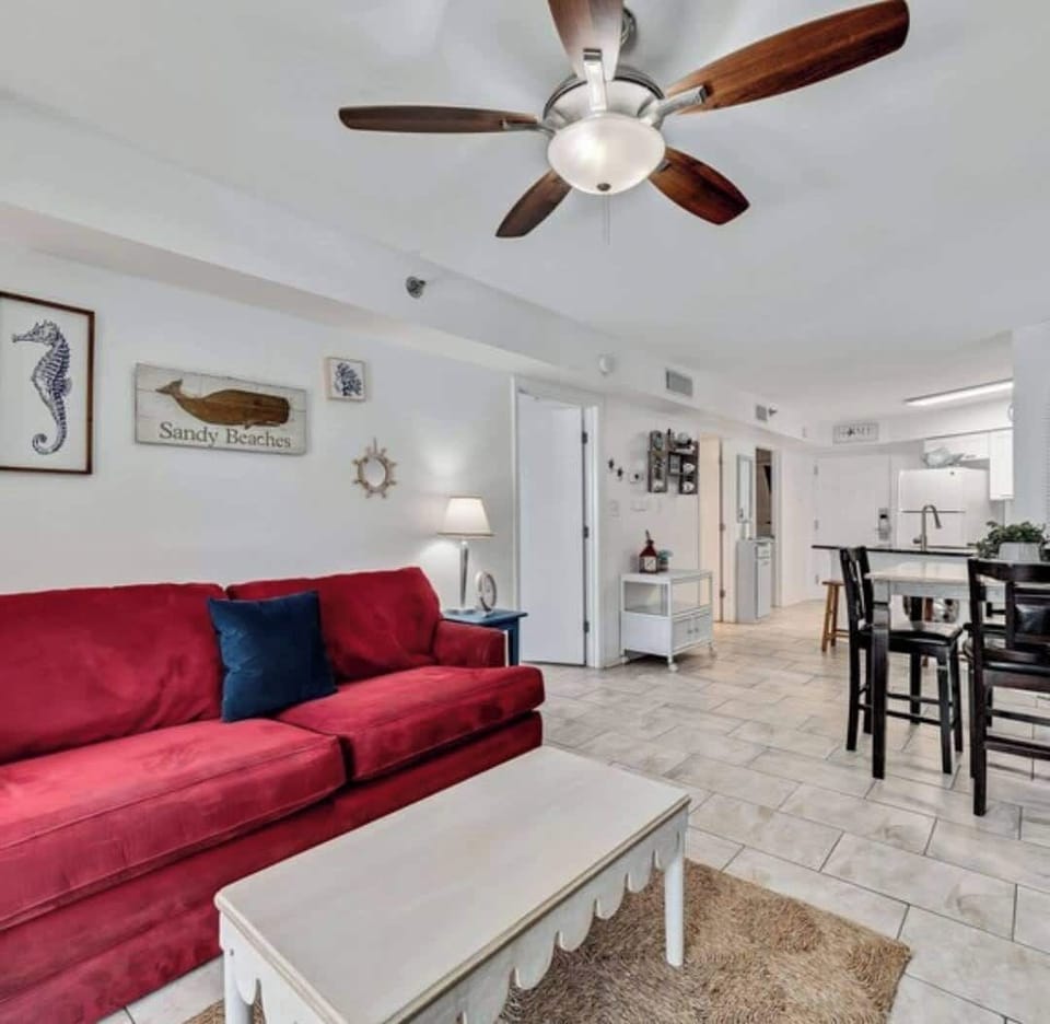 {LIVING ROOM} Relax in the cozy living room with a plush sofa, warm lighting, and easy balcony access. Perfect for crisp fall evenings sip cocoa, watch a movie, or step outside to enjoy the ocean breeze.