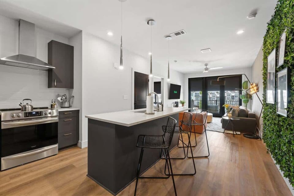 Open-concept living and kitchen area with a large island and a vibrant green accent wall.