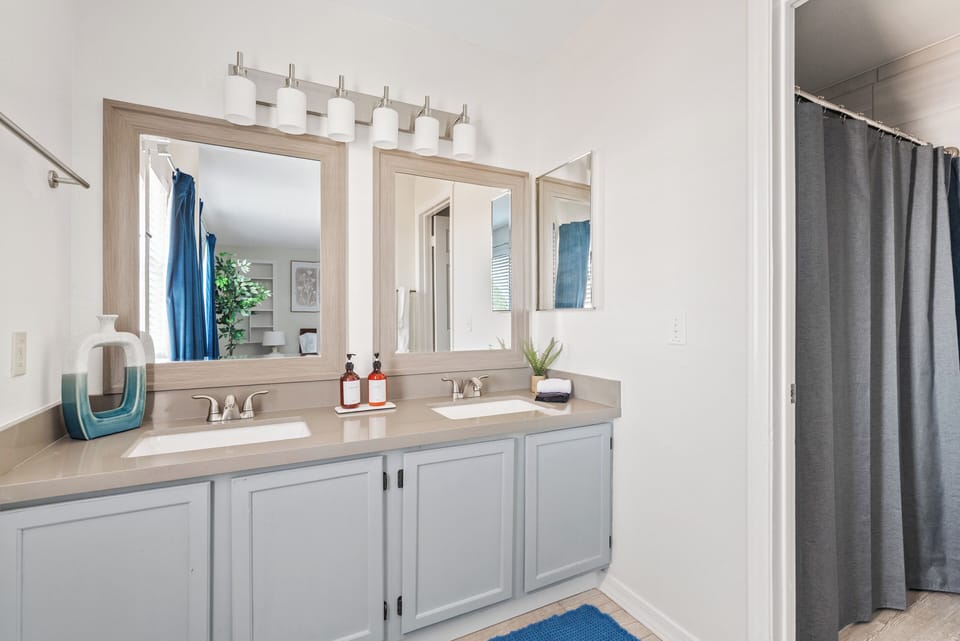 Primary Bathroom:  The ensuite bathroom features dual sinks, a spacious shower, and hotel-quality amenities including shampoo, conditioner, shower gel, lotion, and thoughtful extras like a hairdryer and toothbrushes conveniently stored under the sink
