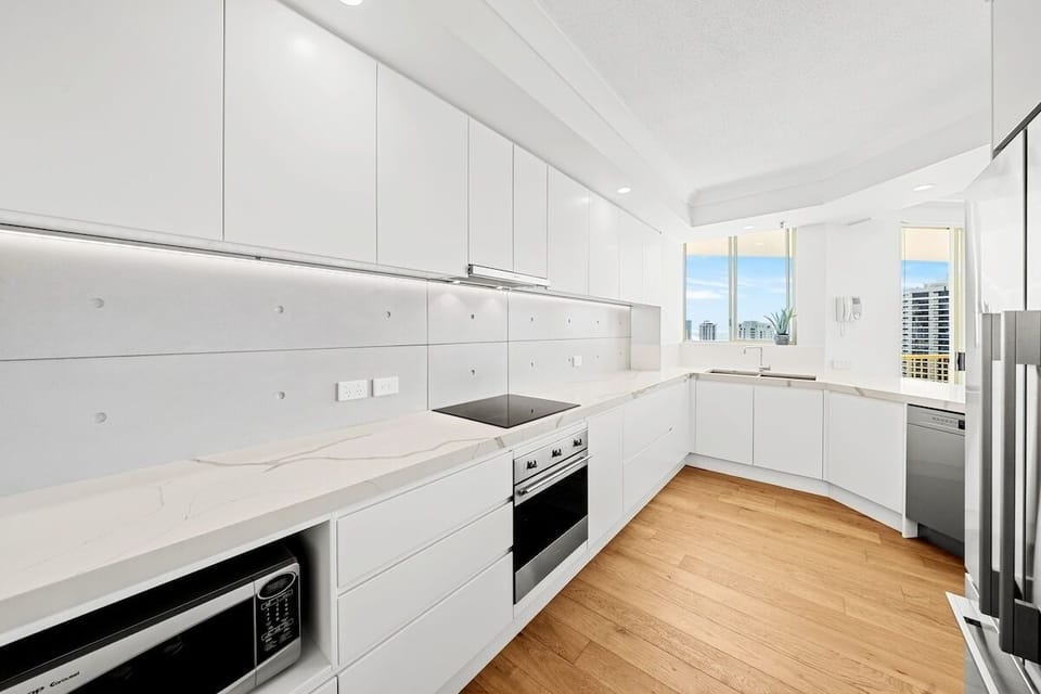 Kitchen with Nespresso, dishwasher, cooktop, oven, and ocean views from windows.
