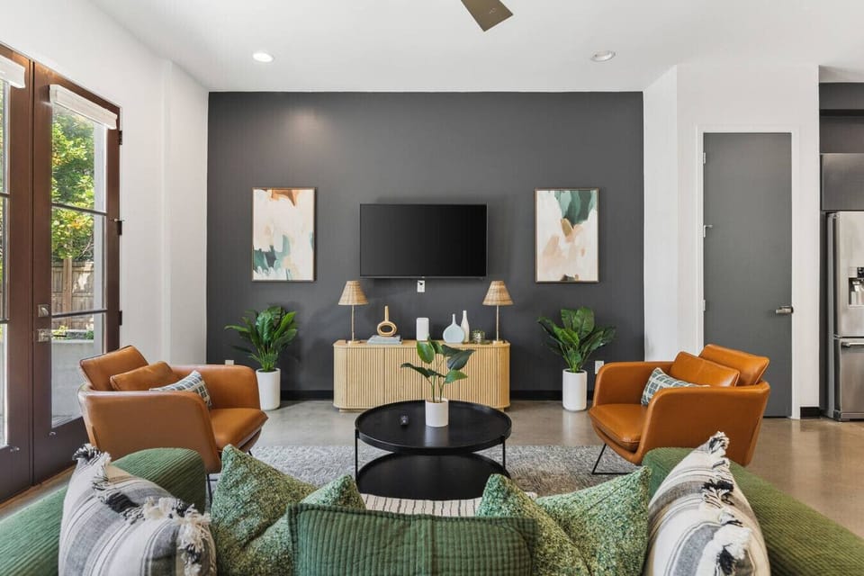 Huge windows and plenty of comfortable seating in the living room with a Smart TV, ceiling fan, and French doors leading out to the community patio & picnic area. The couch doubles as a comfortable Queen pull-out bed.