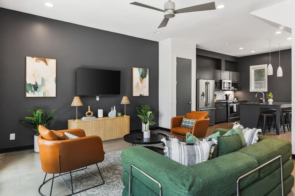 Huge windows and plenty of comfortable seating in the living room with a Smart TV, ceiling fan, and French doors leading out to the community patio & picnic area. The couch doubles as a comfortable Queen pull-out bed.