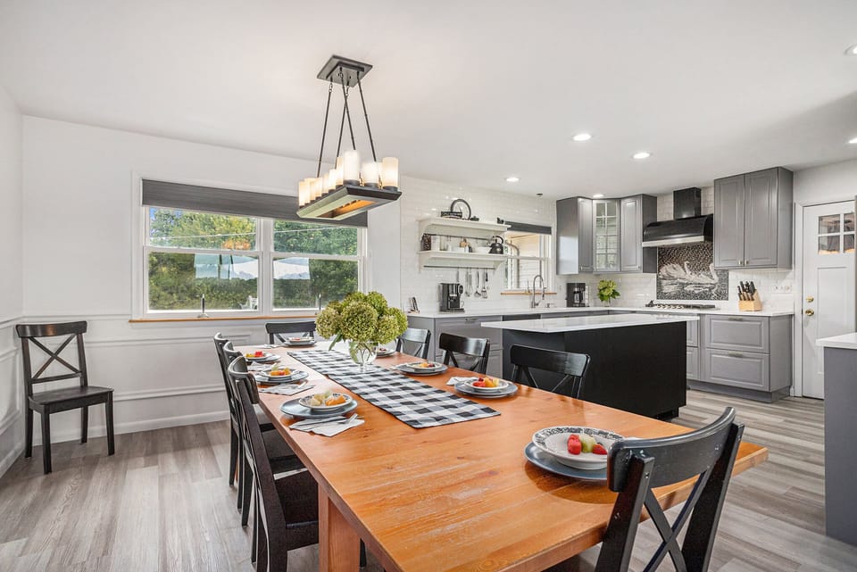 Gather in style! The open kitchen and dining area features modern finishes, a large island, and a warm wood table that comfortably seats 10—perfect for family meals, celebrations, or game nights.