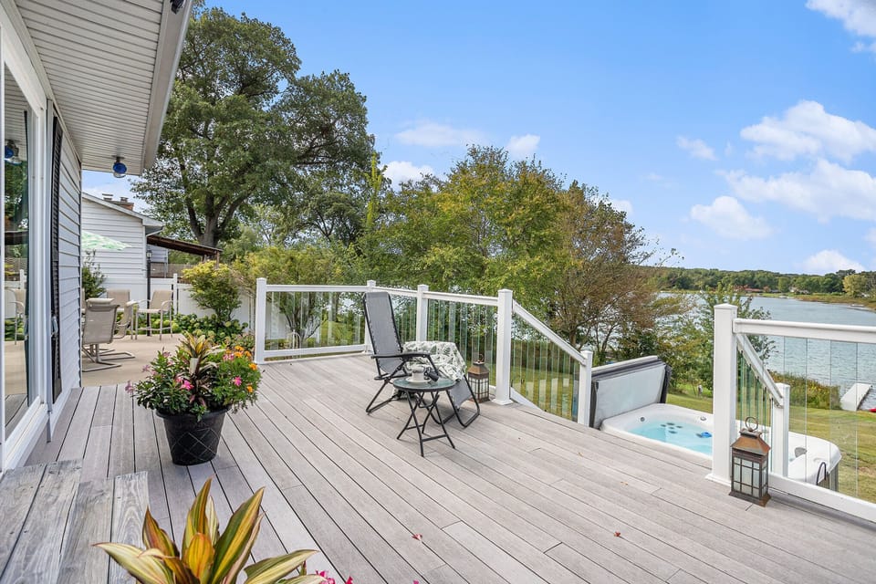 Spacious deck with seating, colorful flowers, and stunning lake views. Relax with morning coffee, unwind in the hot tub below, or use provided binoculars to watch wildlife up close in this peaceful lakeside retreat.