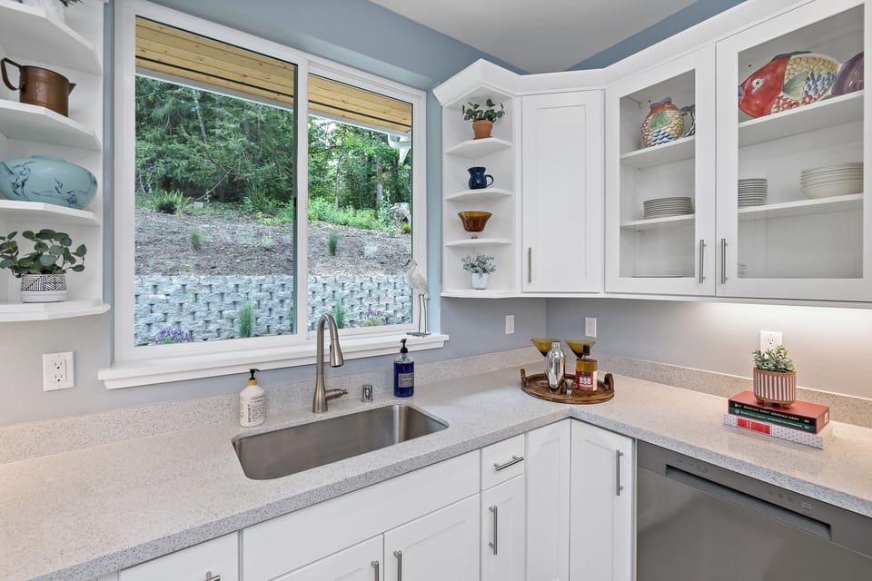 Bright modern kitchen with forest-view window and stylish white cabinetry