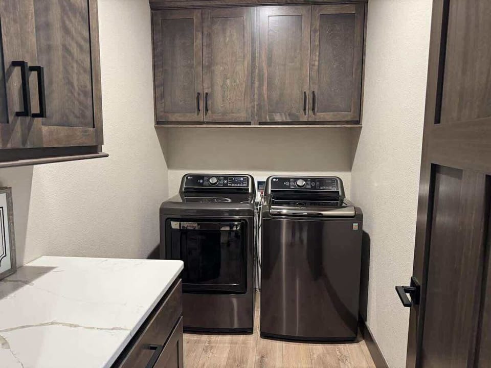 Convenient laundry room with modern washer and dryer, quartz folding counter, and ample cabinet storage—perfect for extended stays or freshening up after a day in the Black Hills.